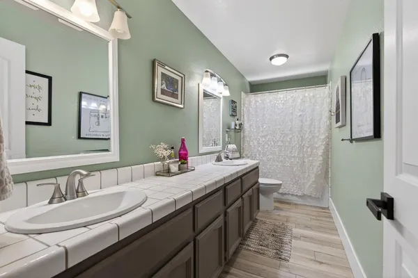 a bathroom with double vanity sinks a toilet a mirror and shower