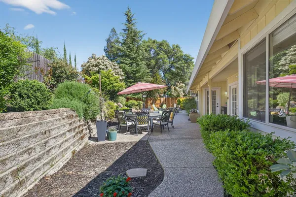 a view of a backyard with table and chairs under an umbrella with potted plants