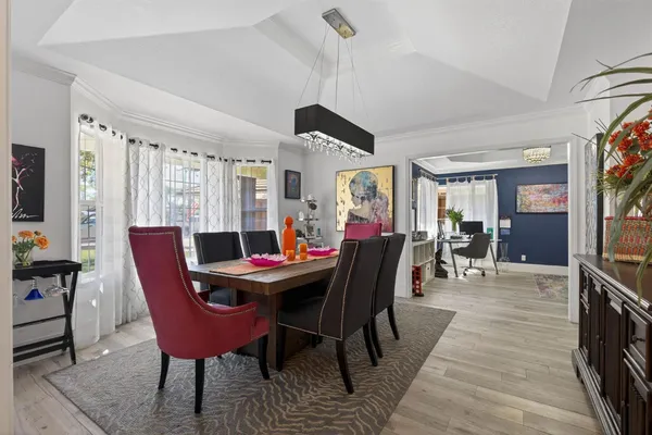 a dining room with furniture a rug a potted plant and a chandelier