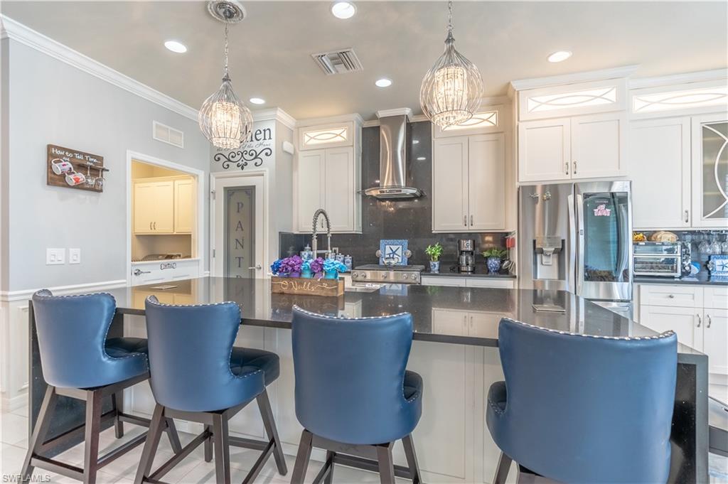 8883 Ravello Court Naples, FL 34114 - Photo 11 of 35 Kitchen with appliances with stainless steel finishes, decorative backsplash, wall chimney range hood, and a kitchen island