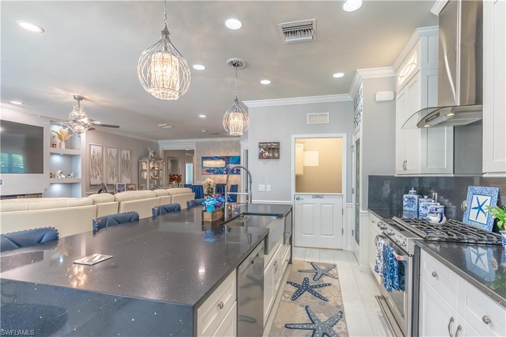 8883 Ravello Court Naples, FL 34114 - Photo 12 of 35 Kitchen featuring wall chimney range hood, sink, white cabinetry, and stainless steel appliances