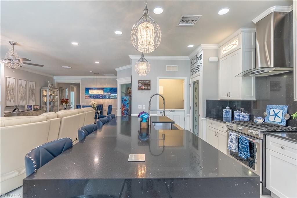 8883 Ravello Court Naples, FL 34114 - Photo 13 of 35 Kitchen with wall chimney range hood, sink, stainless steel range, and an island with sink