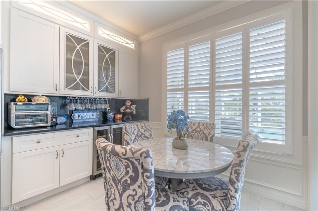 8883 Ravello Court Naples, FL 34114 - Photo 14 of 35 Dining room featuring beverage cooler, crown molding, and light tile patterned floors