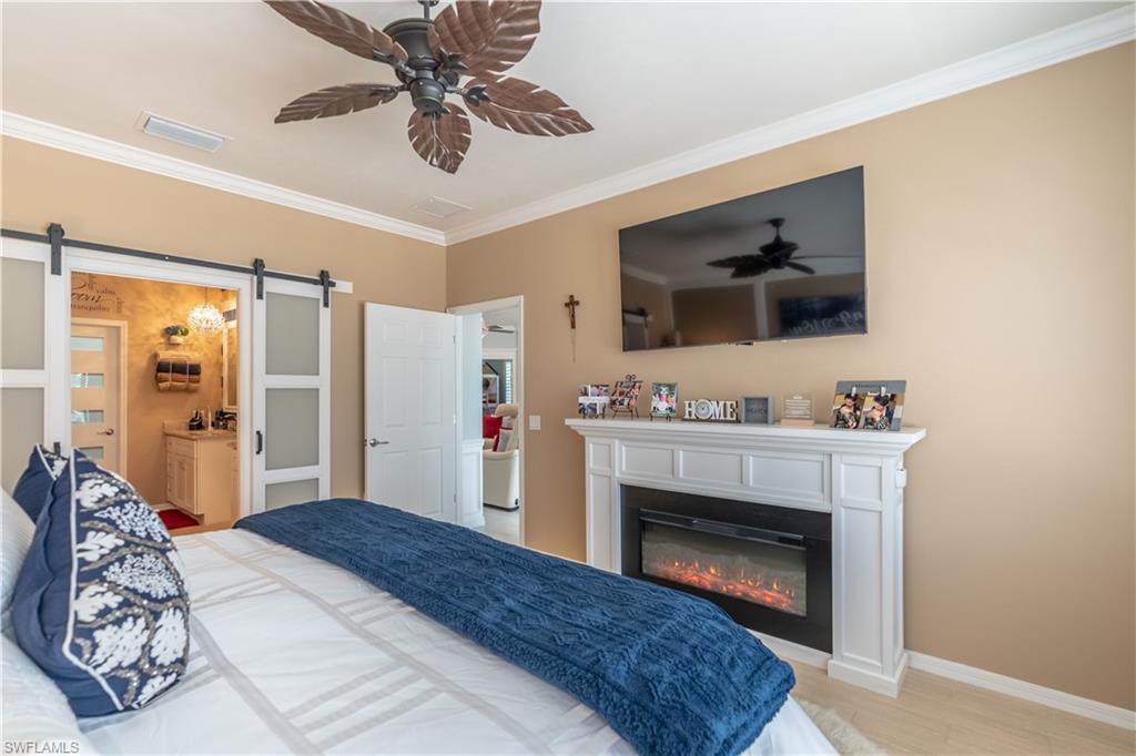 8883 Ravello Court Naples, FL 34114 - Photo 20 of 35 Bedroom with a barn door, connected bathroom, ceiling fan, and crown molding
