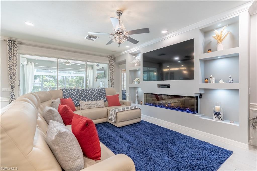 8883 Ravello Court Naples, FL 34114 - Photo 8 of 35 Living room featuring built in shelves, ornamental molding, and ceiling fan