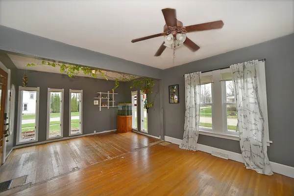 a view of an empty room with window and wooden floor