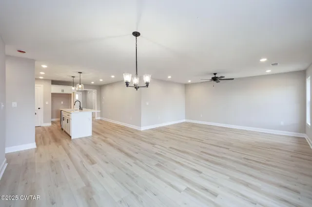 a view of a room with wooden floor and kitchen view