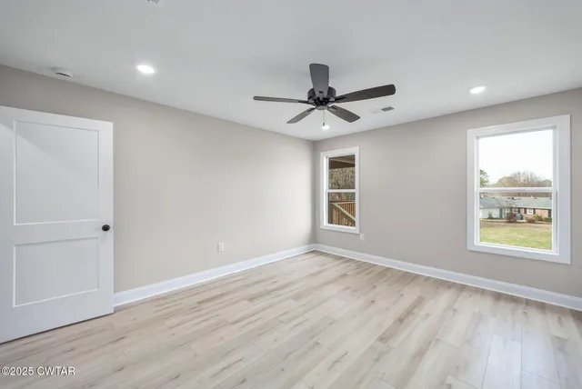 a view of an empty room with a window and wooden floor