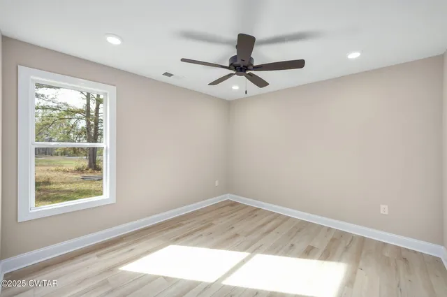 an empty room with a window and a ceiling fan