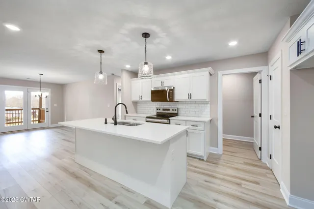 a large kitchen with kitchen island a sink stainless steel appliances and cabinets