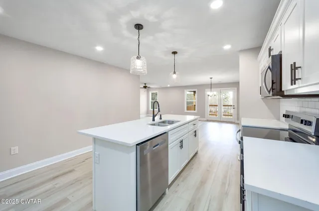 a kitchen with stainless steel appliances granite countertop a sink a stove and a wooden floors