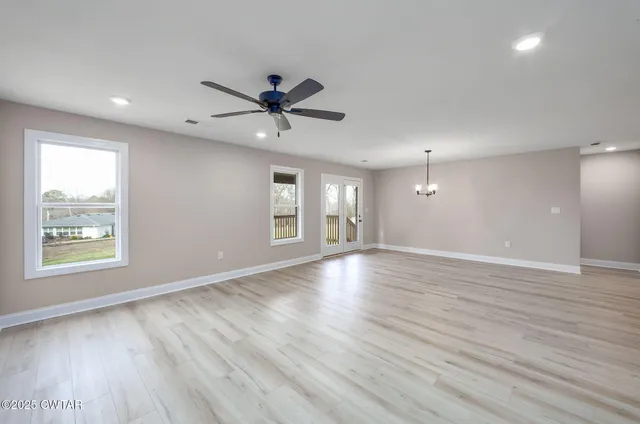 a view of an empty room with a window and wooden floor