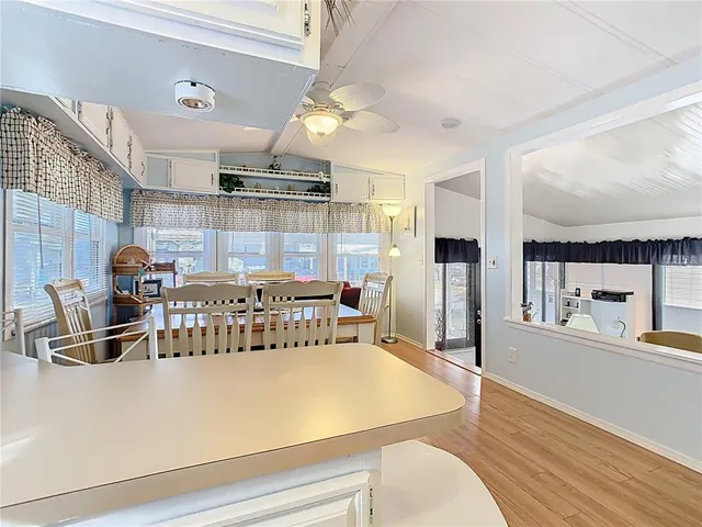 a kitchen with kitchen island a stove a refrigerator and a dining table with wooden floor