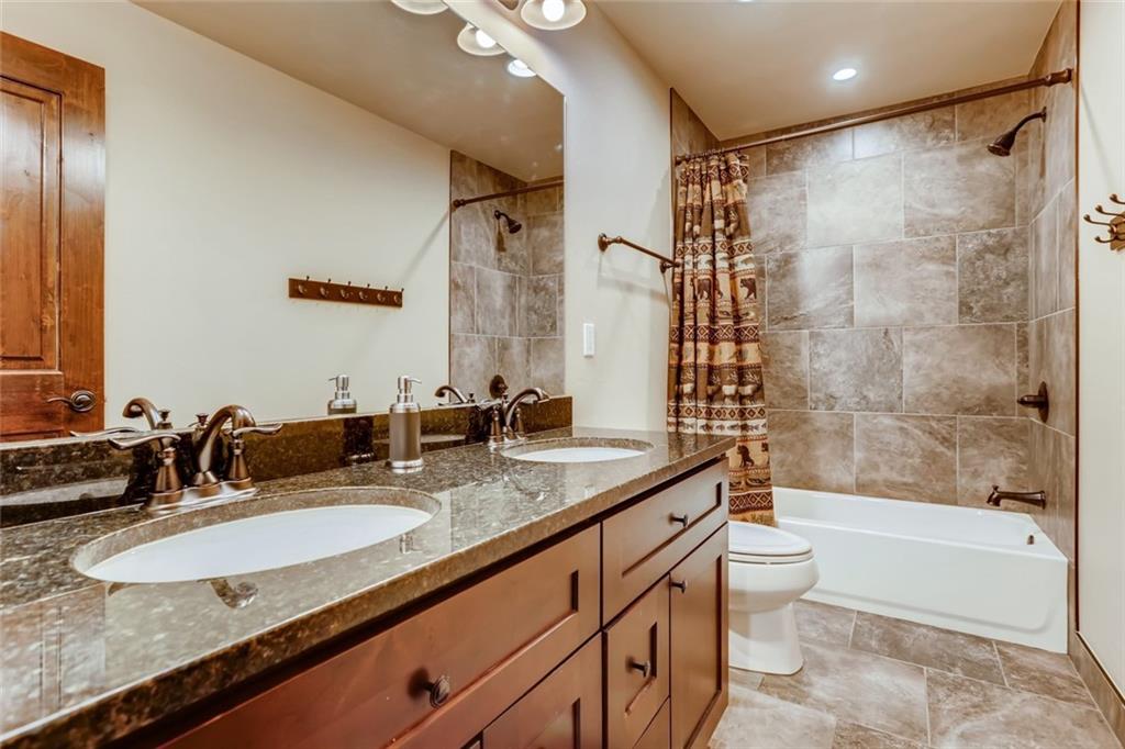 867 Independence Road, Unit 4A Keystone, CO 80435 - Photo 12 of 28 a bathroom with a granite countertop sink a toilet a mirror a bathtub and shower
