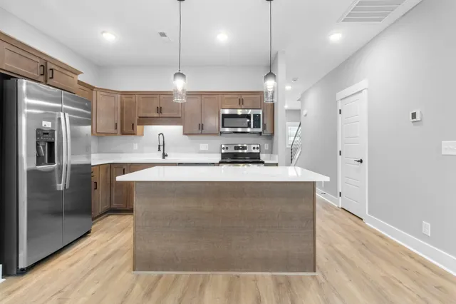 a kitchen with stainless steel appliances granite countertop a refrigerator a sink a stove and oven