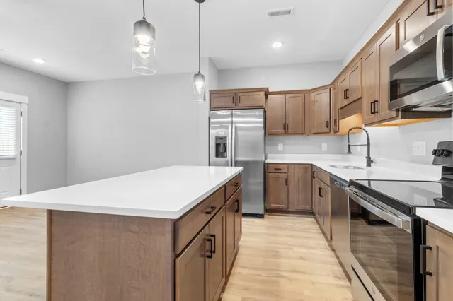 a kitchen with stainless steel appliances granite countertop white cabinets and a sink