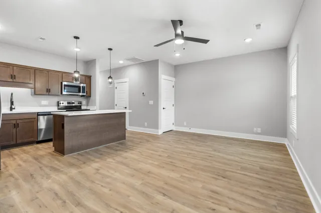 a large kitchen with stainless steel appliances a large counter top a stove a refrigerator and a sink