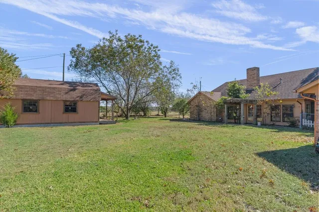 a view of a big house with a big yard and large trees
