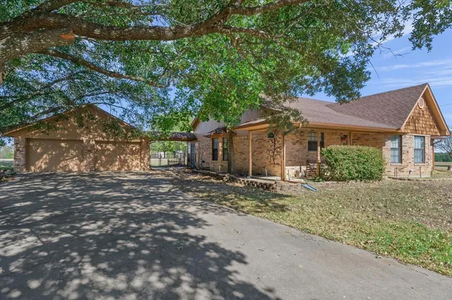 a backyard of a house with large trees and outdoor seating