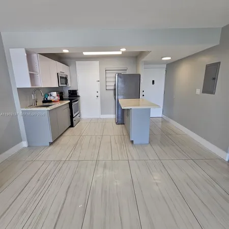 a large kitchen with a large counter top space a sink stainless steel appliances and cabinets