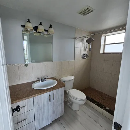 a bathroom with a sink a toilet a mirror and shower