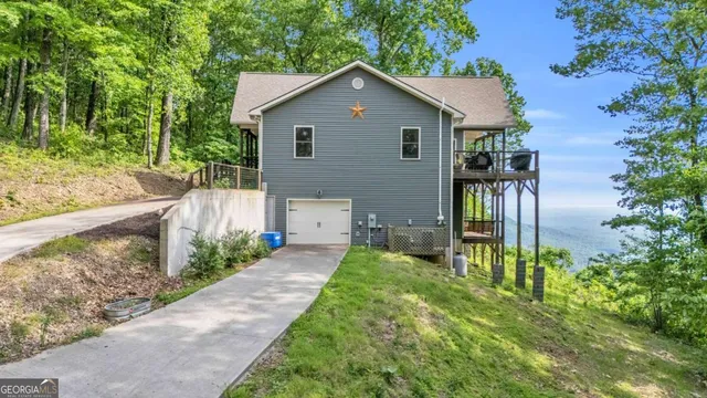 a view of a house with a small yard plants and large trees