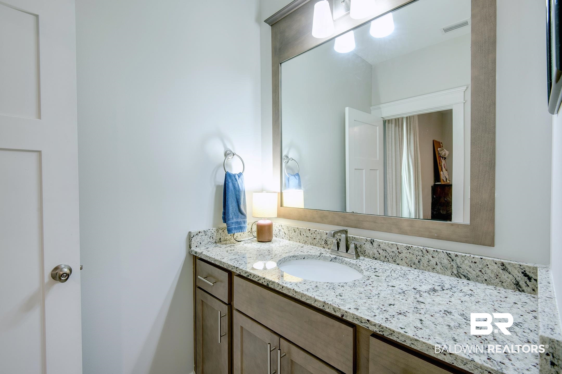 18754 Treasure Oaks Road Gulf Shores, AL 36542 - Photo 36 of 53 Bathroom vanity featuring a speckled countertop, undermount sink, and a framed mirror