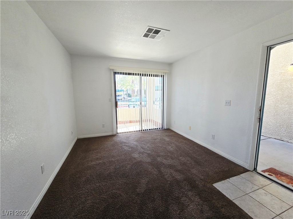 5211 South Lindell Road, Unit 104 Las Vegas, NV 89118 - Photo 3 of 12 Spare room featuring dark carpet, a textured wall, and a textured ceiling