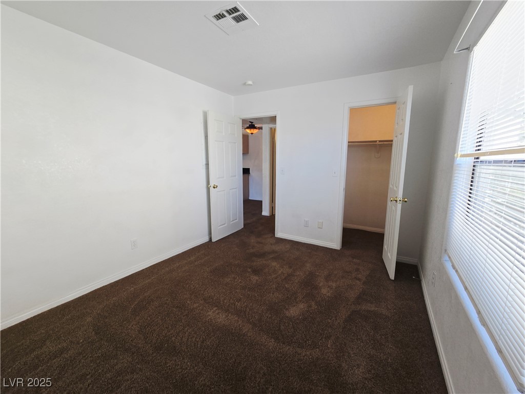 5211 South Lindell Road, Unit 104 Las Vegas, NV 89118 - Photo 10 of 12 Unfurnished bedroom with dark carpet and a spacious closet