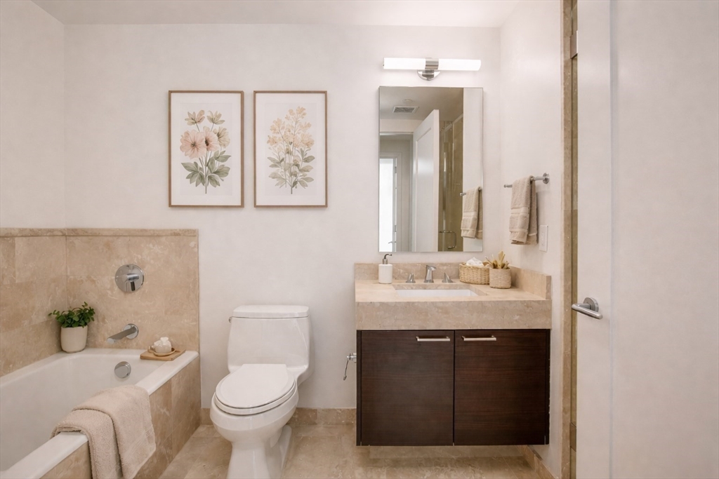 1 Franklin Street, Unit 1714 Boston, MA 02110 - Photo 7 of 10 a bathroom with a granite countertop toilet a sink and a mirror