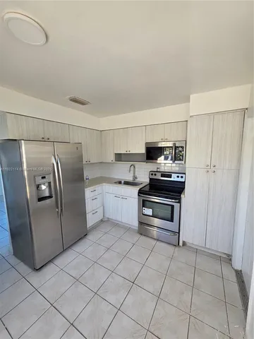 a kitchen with a refrigerator sink and cabinets