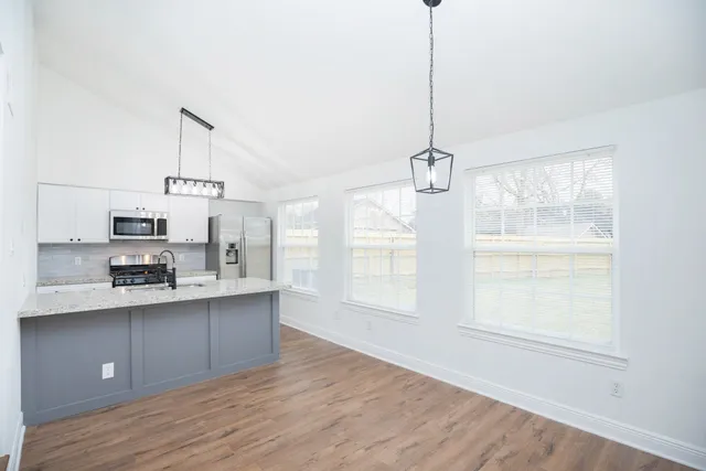 a kitchen with stainless steel appliances a sink stove and wooden floor