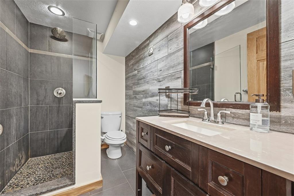 5380 Hardt Road Gibsonia, PA 15044 - Photo 32 of 49 A 4th full bathroom in the basement has shiplap walls, walk in tiled shower with stone floor and vanity.