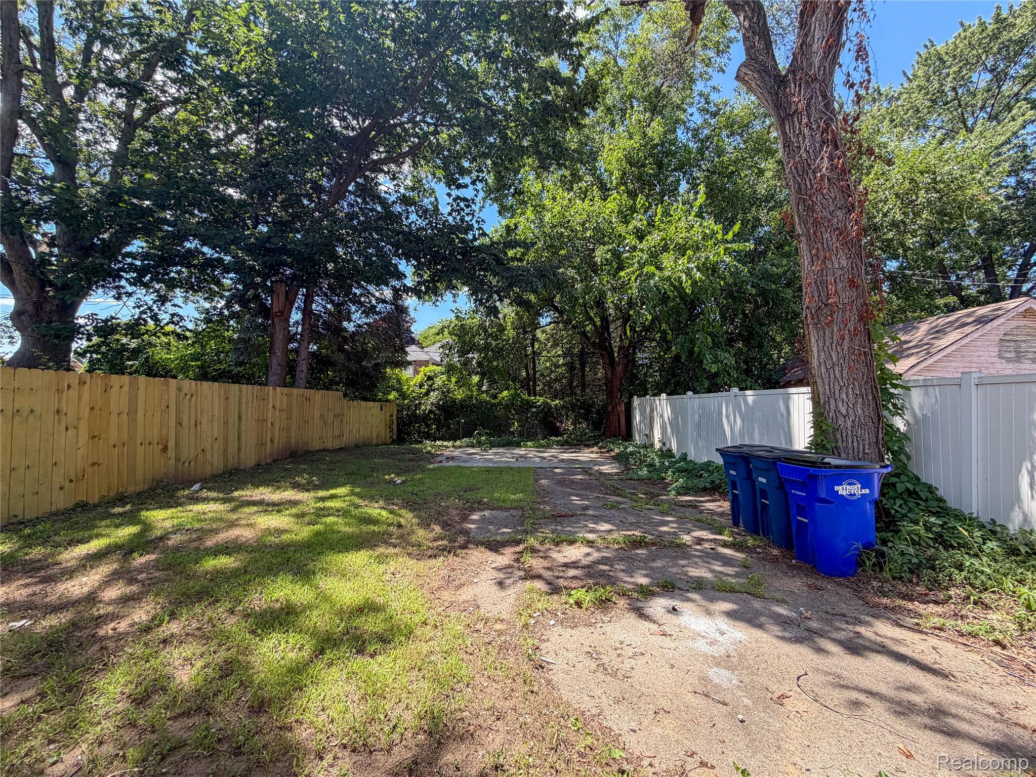 18217 Prairie Street Detroit, MI 48221 - Photo 30 of 34 Expansive backyard featuring a newly installed privacy fence, mature trees, and a gravel and grass surface