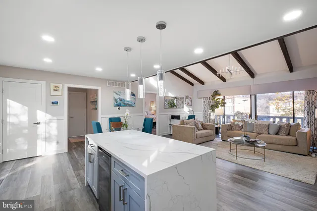 a large living room with stainless steel appliances furniture a rug and a large window