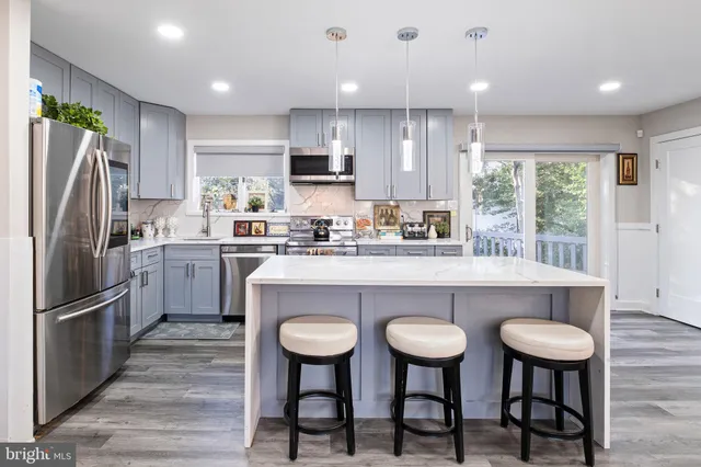 a kitchen with stainless steel appliances a table chairs refrigerator and microwave