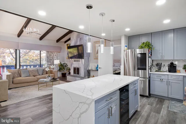 a large kitchen with stainless steel appliances kitchen island granite countertop a refrigerator a oven a island and couches with wooden floor