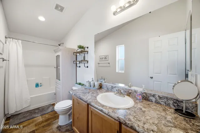 a bathroom with a granite countertop sink toilet a mirror and shower