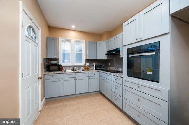a kitchen with granite countertop white cabinets a sink a window and stainless steel appliances