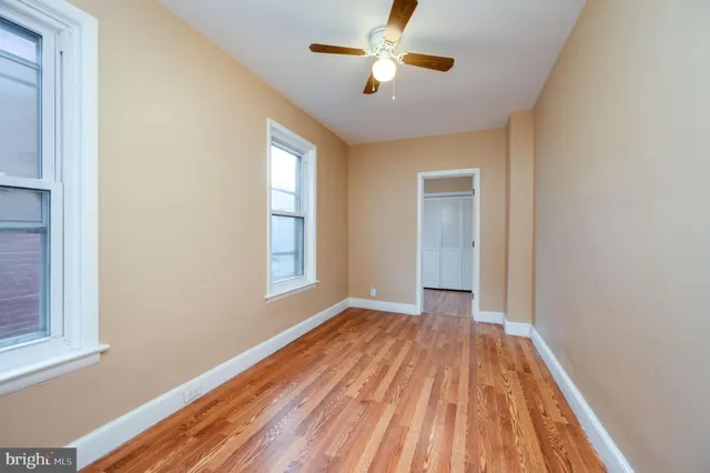 an empty room with wooden floor cabinet and windows