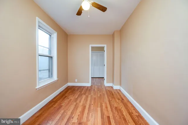 a view of empty room with wooden floor and fan