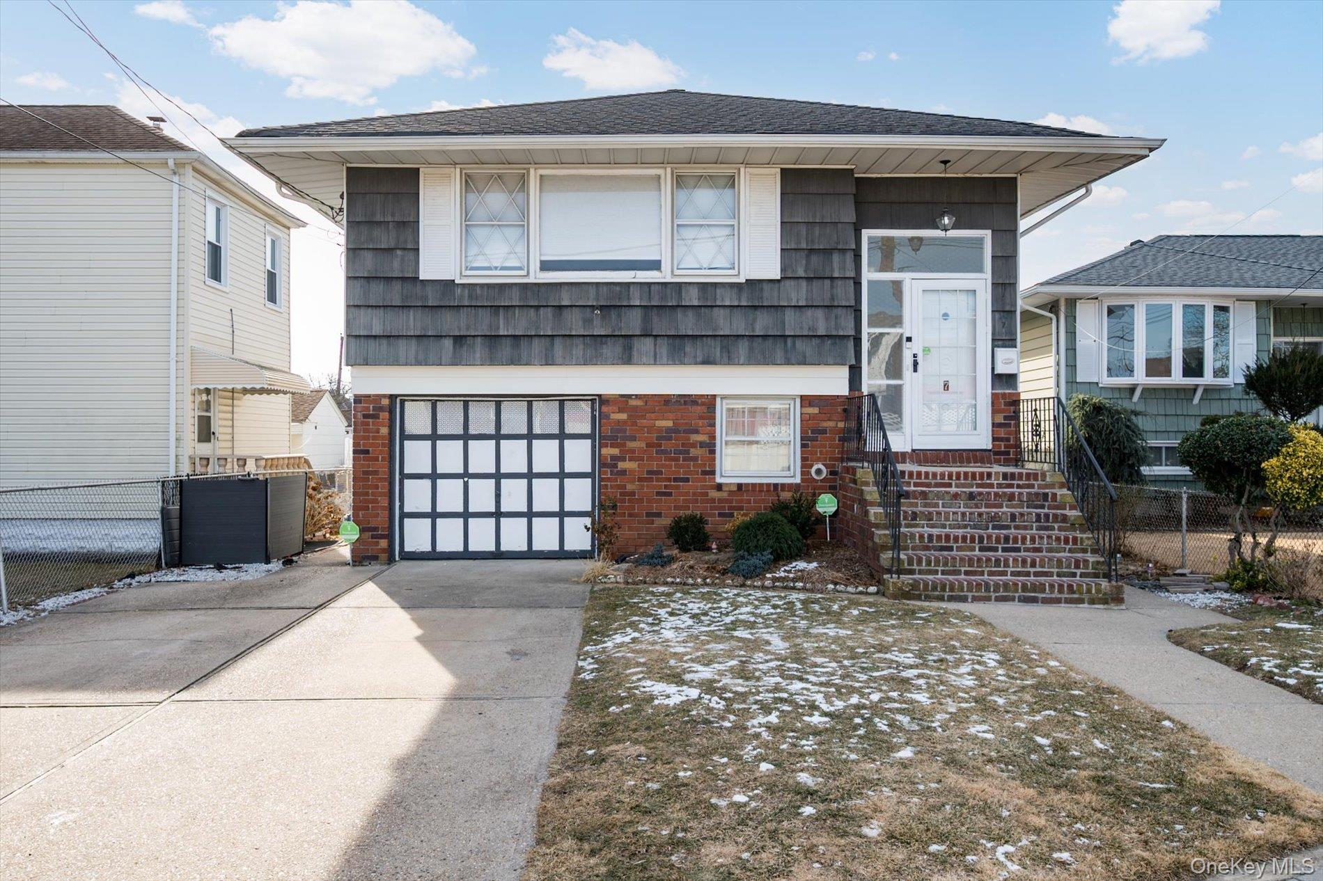 High ranch home with an attached garage, brick siding, and concrete driveway