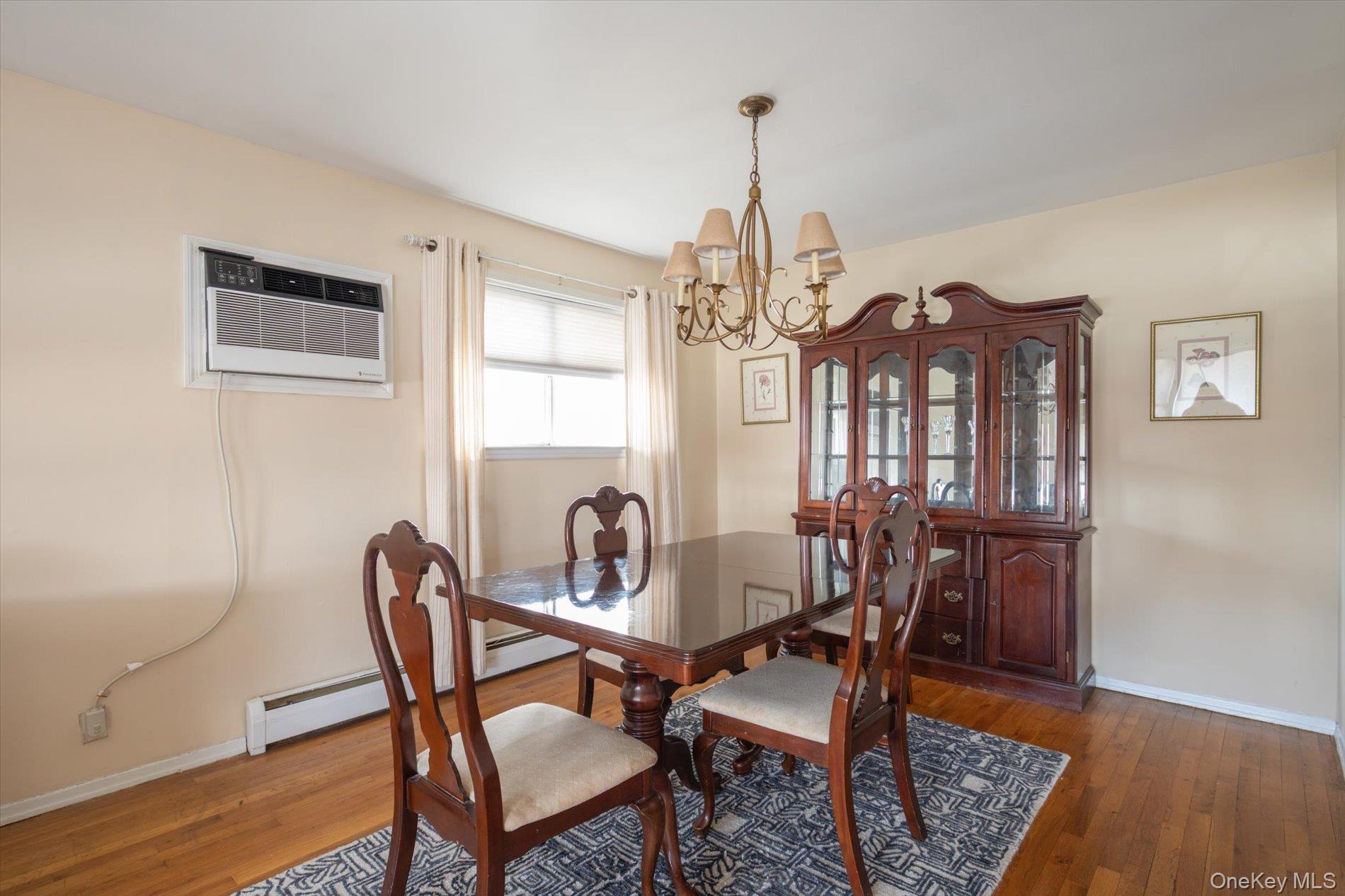 7 Stein Street Valley Stream, NY 11580 - Photo 6 of 27 Dining area featuring hardwood / wood-style floors, a chandelier, a wall mounted air conditioner, and a baseboard radiator