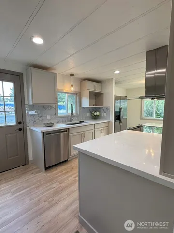 a kitchen with stainless steel appliances a sink a stove a refrigerator cabinets and a window