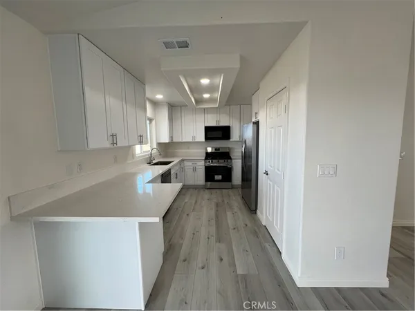 an empty room with wooden floor fireplace and windows