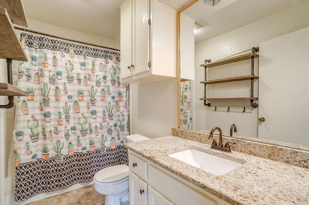 709 North Ave B Springtown, TX 76082 - Photo 17 of 32 a bathroom with a granite countertop sink toilet a mirror and shower curtain