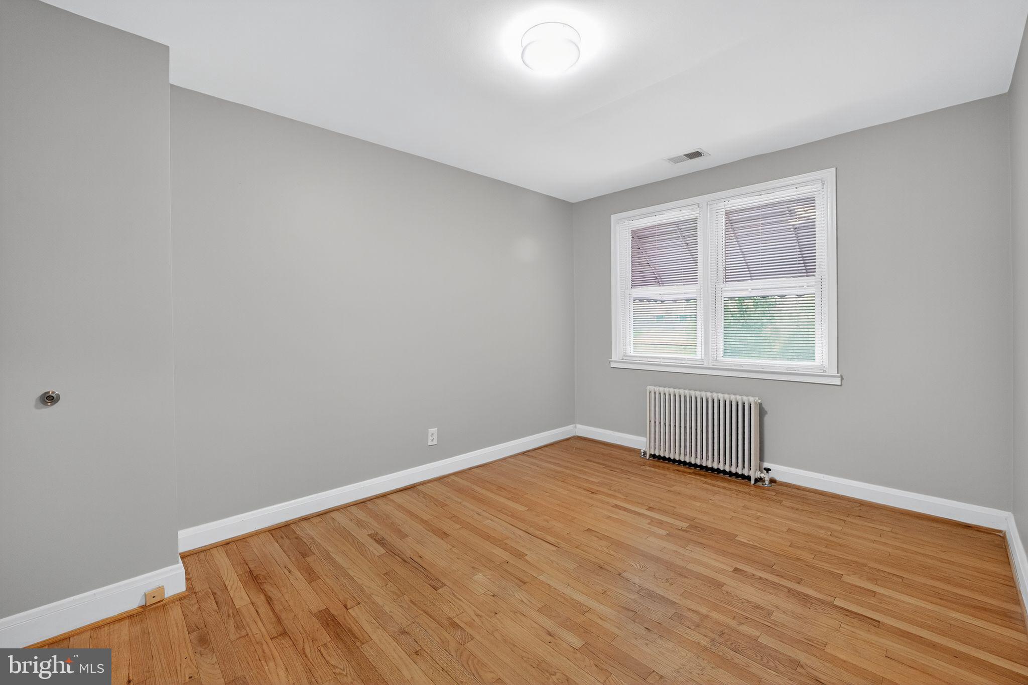 1017 Wicklow Road Baltimore, MD 21229 - Photo 9 of 34 an empty room with wooden floor and windows