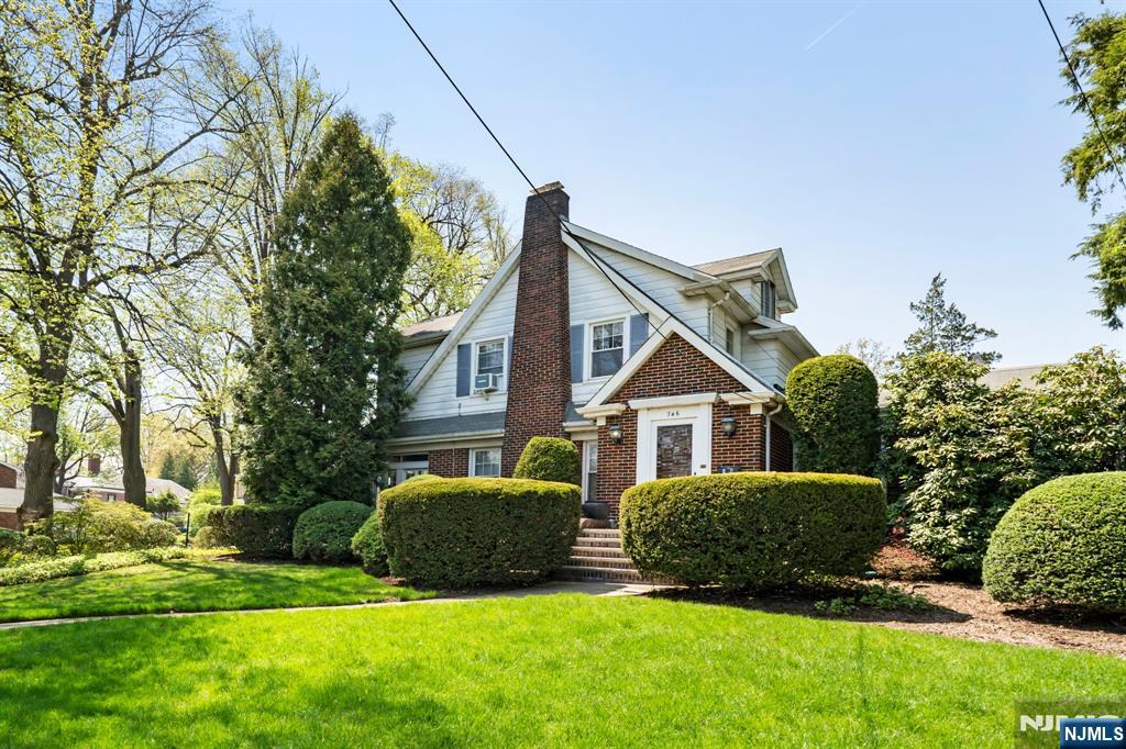a view of a house with a big yard plants and large trees