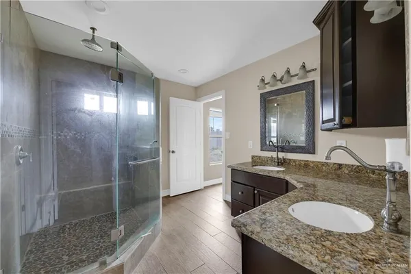 a bathroom with a granite countertop sink a mirror and shower