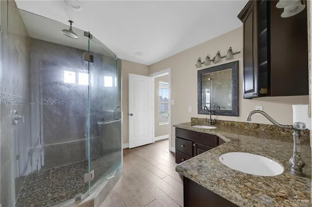 a bathroom with a granite countertop sink a mirror and shower